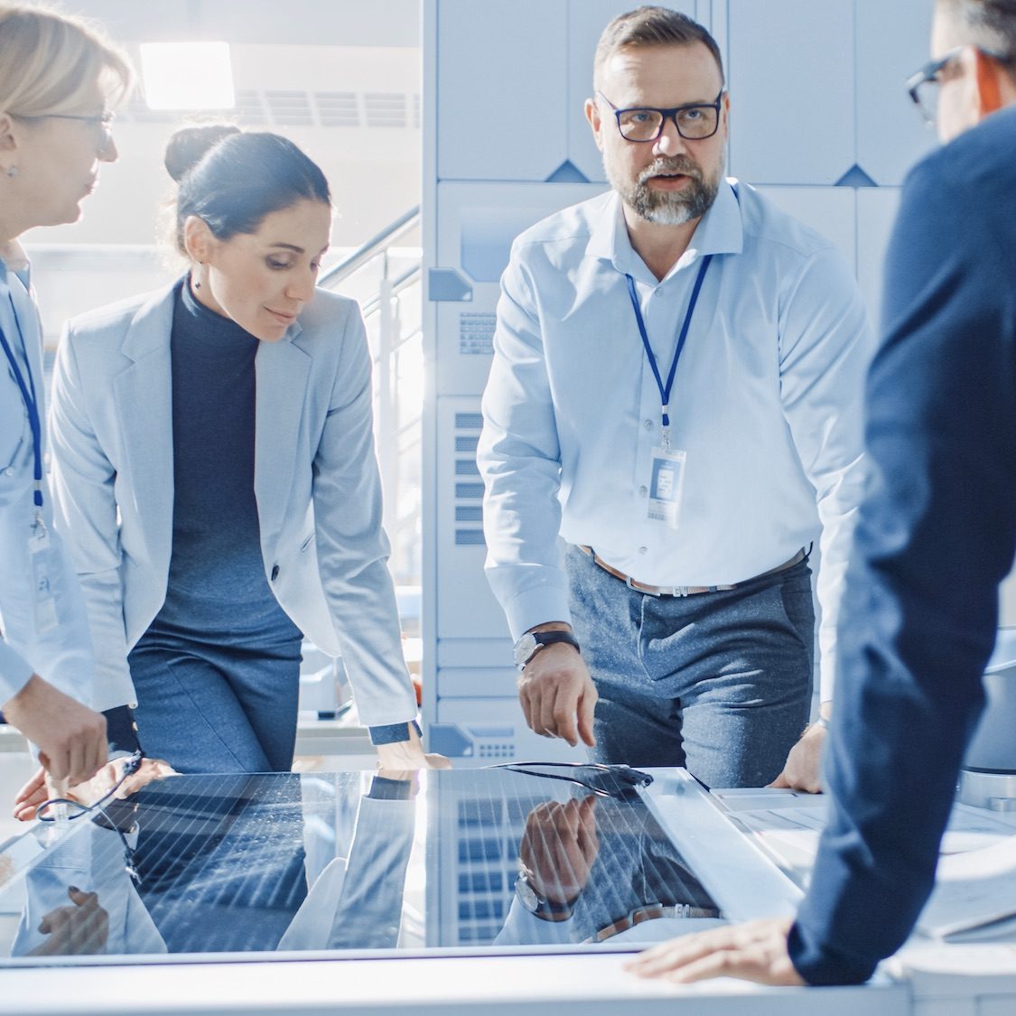 Team Meeting of Renewable Energy Engineers Working on an Innovative More Efficient Solar Panel Battery Concept. Group of Specialists Gathered Around Table, Solving Problems. Bright Research Facility